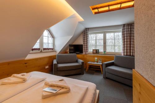 a hotel room with a bed and two chairs at Hotel & Restaurant Waldblick in Pulsnitz