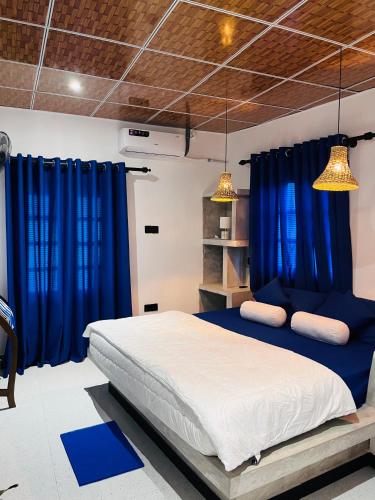 a bedroom with blue curtains and a large bed at Harsha Villa Dickwella in Dickwella