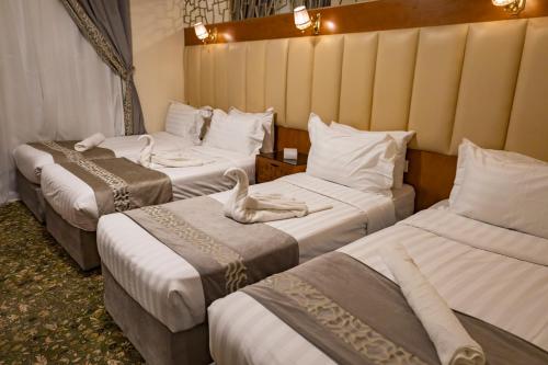 a hotel room with three beds with a swan on them at Grand Zowar Hotel - فندق جراند زوار للضيافة السياحي in Medina