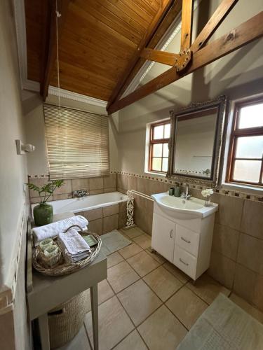 a bathroom with a sink and a tub and a mirror at Zwartmodder Clarens in Clarens