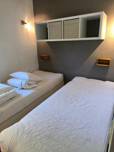 two beds in a small room with white sheets at Bungalows du Lac de Rabais in Virton