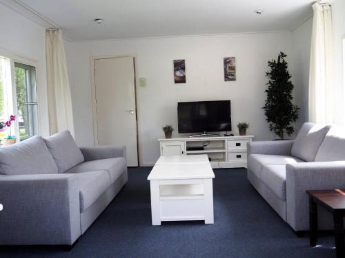 a living room with two couches and a tv at Woonboot de Waterwoning in Irnsum