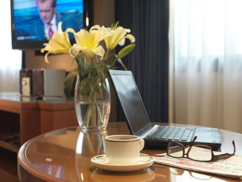 a table with a vase of yellow flowers and a laptop at Concorde Hotel Kuala Lumpur in Kuala Lumpur