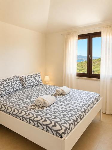a bedroom with a large bed with a window at Residence Borgo Punta Villa in La Maddalena