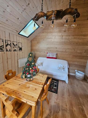 a room with a table and a christmas tree in it at Le chalet chartreux in Sarcenas