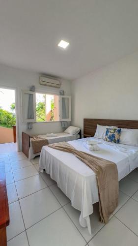 a large bedroom with two beds and a window at Pousada Do Joe in Morro de São Paulo