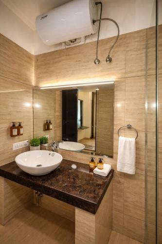 ein Badezimmer mit Waschbecken und großem Spiegel in der Unterkunft Tata Vista By Vaikunth - McLeod Ganj-Centrally Heated & Air Cooled # Near Mall Road # Big Parking # Lift #Spacious Rooms # Most Awarded # Property Of The Year # in Dharamshala