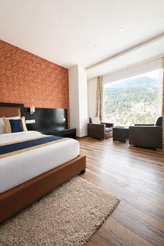 ein Schlafzimmer mit einem großen Bett und einem großen Fenster in der Unterkunft Tata Vista By Vaikunth - McLeod Ganj-Centrally Heated & Air Cooled # Near Mall Road # Big Parking # Lift #Spacious Rooms # Most Awarded # Property Of The Year # in Dharamshala