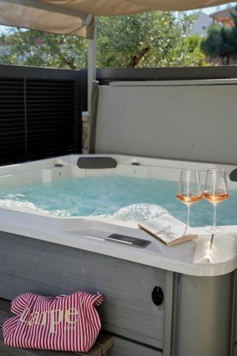 a hot tub with two glasses of wine at Apartments & Villa Tisno in Obrovac