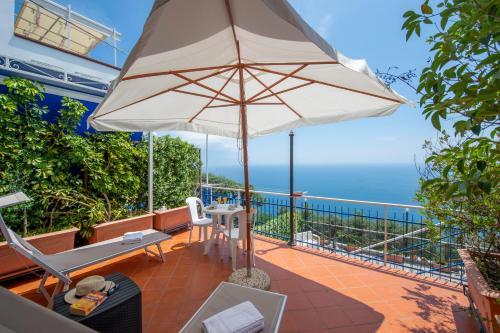 a patio with an umbrella and the ocean at Sogno Blu in Furore