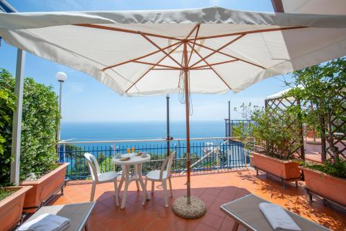 a patio with an umbrella and a table and chairs at Sogno Blu in Furore