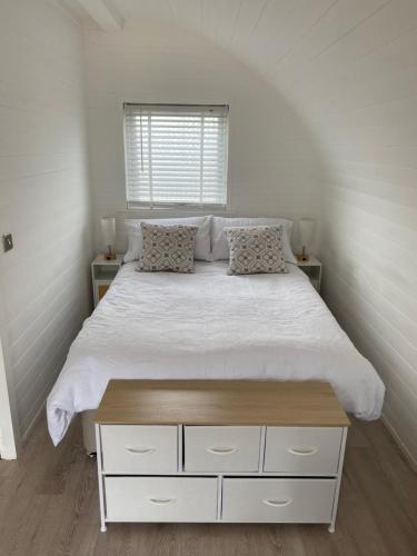 a bedroom with a large bed with white sheets and a window at Braehead Pods in Forth