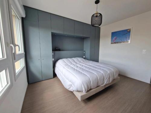 a bedroom with a large white bed with blue walls at La Perle bleue in Berck-sur-Mer