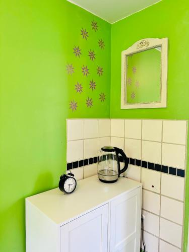 a kitchen with a green wall with a blender on a cabinet at Systrarna på Kivik in Kivik