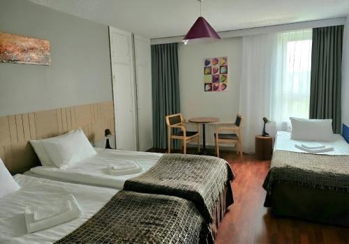 a hotel room with two beds and a table at Hotel Suonenjoki in Suonenjoki