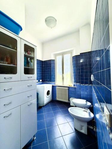 a blue tiled bathroom with a sink and a toilet at Domus Dafne Apartment in Senigallia