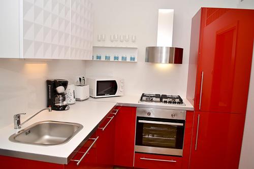 a kitchen with red cabinets and a sink at Classic 2BDR suite by Ruterra in Prague