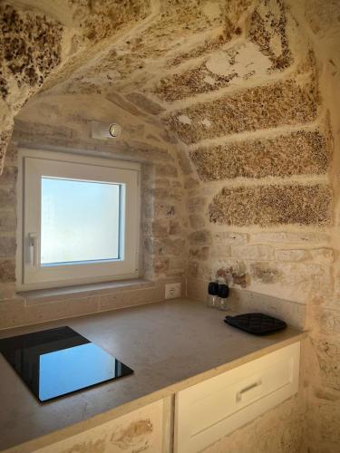 a kitchen with a window in a stone wall at Al Settimo Chilometro in Gioia del Colle