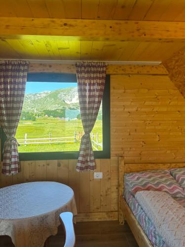 a bedroom with a window in a log cabin at Mountain peaceful cottages in Žabljak