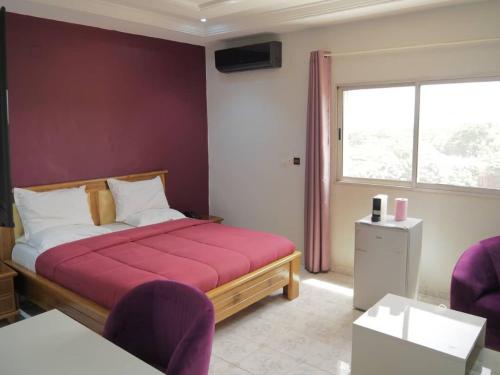 a bedroom with a bed and a window and purple chairs at OABY'S Hôtel in Bobo-Dioulasso