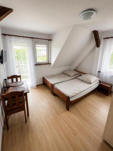 a bedroom with a bed and a table and windows at Pensjonat Rowy Blisko Morza in Rowy
