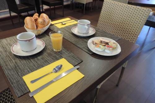 a table with plates of food and cups of coffee and bread at Hôtel de France in Espalion