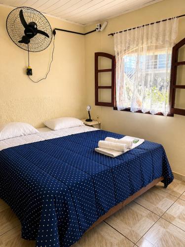 a bedroom with a blue bed with a fan at Pousada Viva Mar in Saquarema