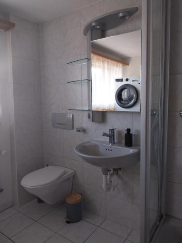 a bathroom with a sink and a toilet and a mirror at 1 Zimmer Unterkunft in Spiez