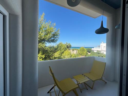 a balcony with two chairs and a table and a window at Casa Mediterranea al mare, Jacuzzi, Torre Guaceto, Ostuni in Specchiolla