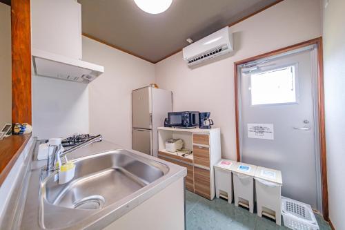 a kitchen with a sink and a refrigerator at がじゅまる Miyako Hotel in Miyakojima