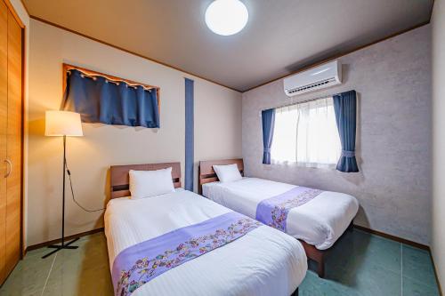 a room with two beds and a window at がじゅまる Miyako Hotel in Miyakojima