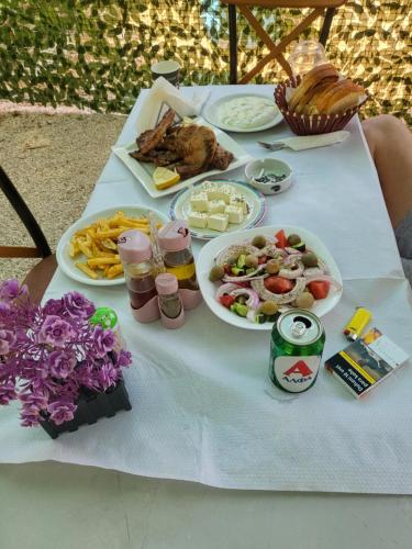 a table with plates of food and drinks on it at Micro Africa Camping Site in Delvinë