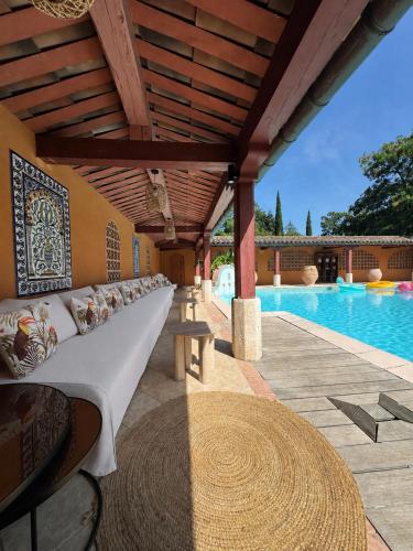 a couch sitting under a pergola next to a pool at L'Hacienda in Mialet