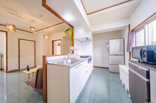 a kitchen with a sink and a refrigerator at キジムナー MIYAKO Hotel in Miyakojima