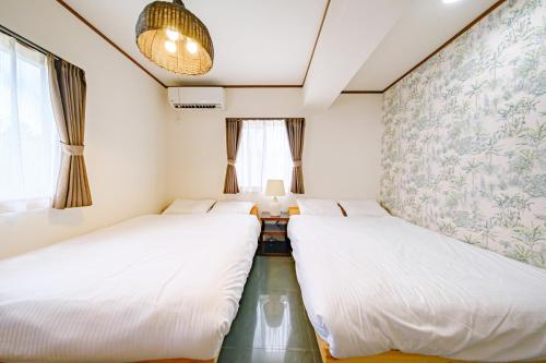 two beds in a small room with a window at キジムナー MIYAKO Hotel in Miyakojima