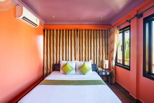 a bedroom with a bed with orange walls and windows at Golden Butterfly Villa in Siem Reap