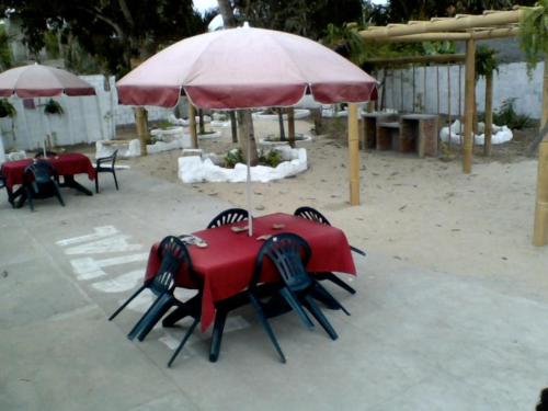 a group of tables and chairs under an umbrella at Hostal Surf Olón in Olón