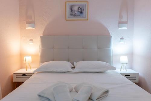 a bedroom with a white bed with two towels on it at Corfu Dream Holidays Villas in Glyfada