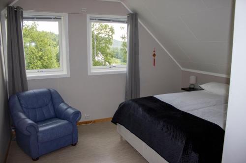 a bedroom with a bed and a chair and two windows at Villa Valentina by Arctic Prive - Northern Lights Villa with Sauna & Fjord View in Alta in Alta