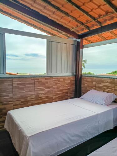 a bedroom with a large bed and two windows at Casa do Seu Lourenço in Beberibe