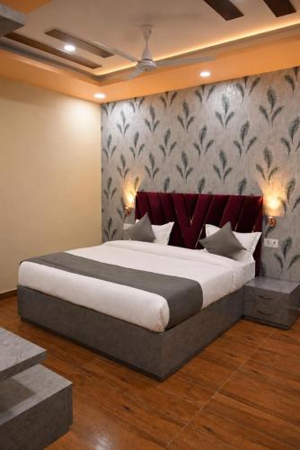 a bedroom with a large bed with a red headboard at HOTEL RAAS PLAZa in Kānpur