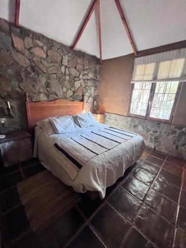a bedroom with a bed and a stone wall at Alcohuaz Indomito in Alcoguaz