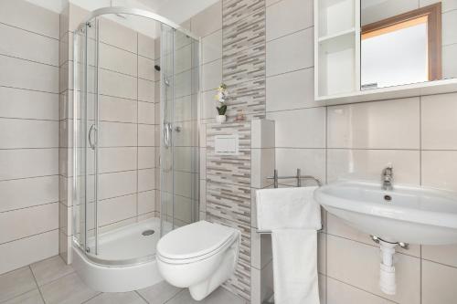 a white bathroom with a toilet and a sink at Hołcyna 21 in Brenna