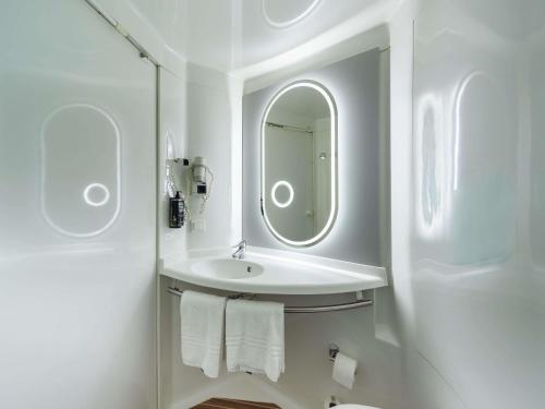 a white bathroom with a sink and a mirror at Ibis Murcia in Murcia