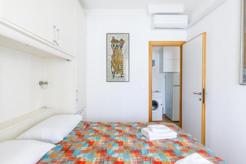 a white room with a bed with a colorful blanket at Piscina Gratis, Pool View Oasis Pool View in Lido Adriano
