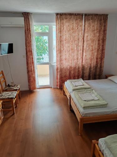 a bedroom with two beds and a large window at Zlatevi Guest House in Obzor