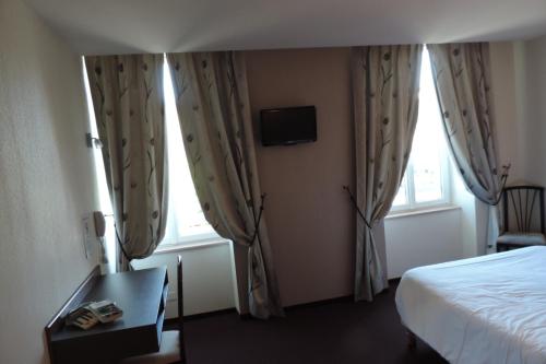 a hotel room with a bed and two windows at Hôtel de France in Espalion