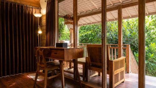a dining room with a table and chairs and a large window at Indraprastha 2 Bungalow in Ubud