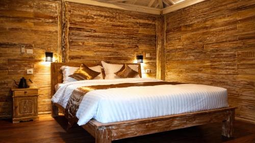 a bedroom with a bed in a wooden wall at Indraprastha 2 Bungalow in Ubud