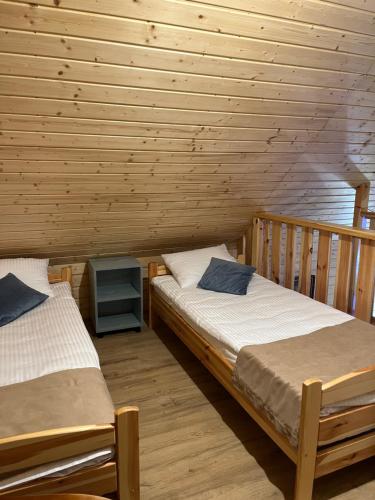 two beds in a room with wooden walls at Brzozowe Zacisze in Narol